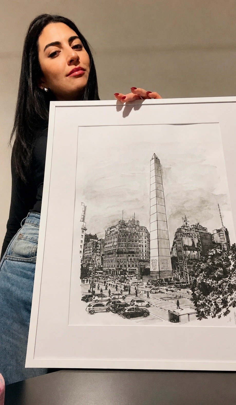 Natalia Peña sosteniendo una obra arquitectónica enmarcada