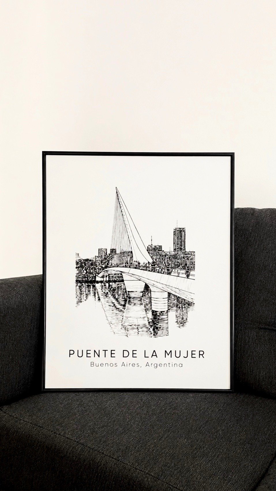 Obra Puente de la Mujer enmarcada y apoyada sobre un sofá oscuro